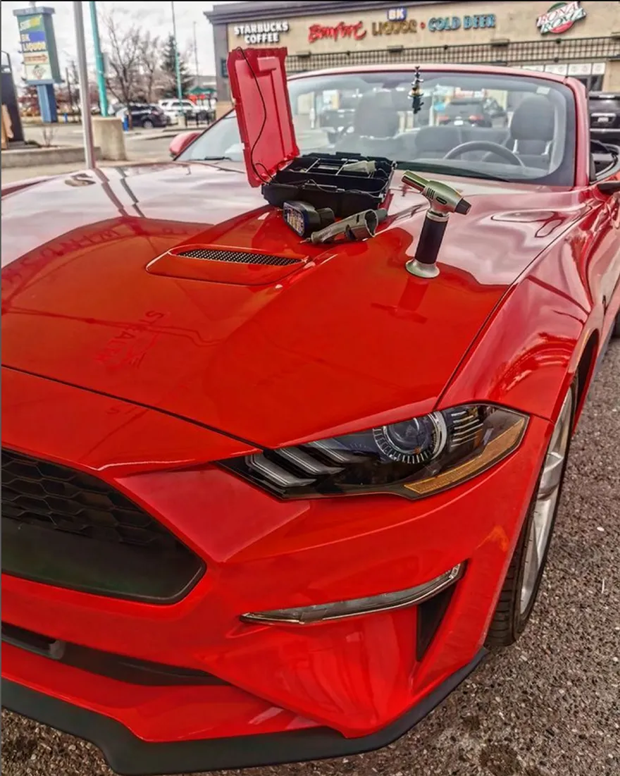 A red, convertable Shelby Mustang after a windshieeld reepair jjob at a Stealth Windshields Repair tent