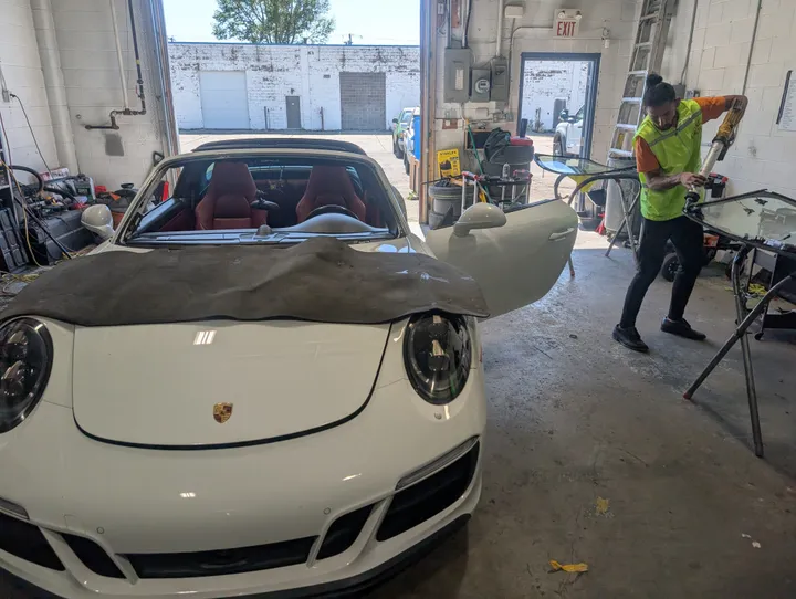 Windshield replacement in-progress of a white Porsche Cayman at s Stealth garage