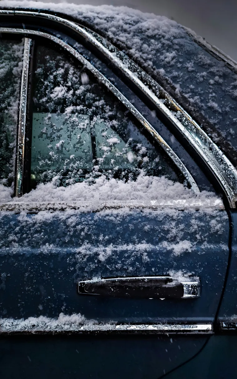 A blue car under heavy frosting due to cold and snowy weather