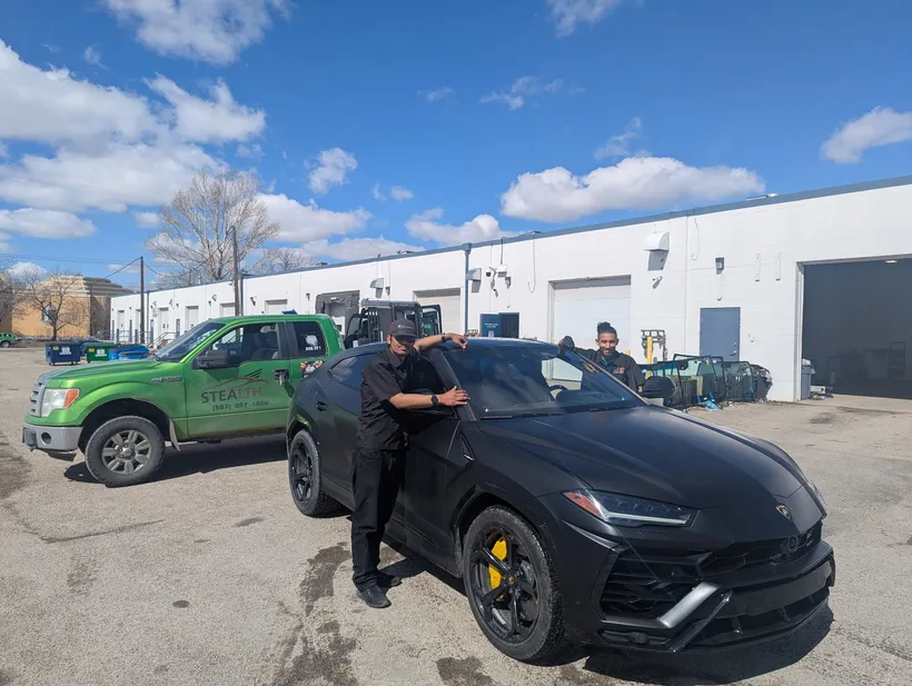 Stealth technician on a mobile repair fixing a windshield chip on a black Lamborghini Urus